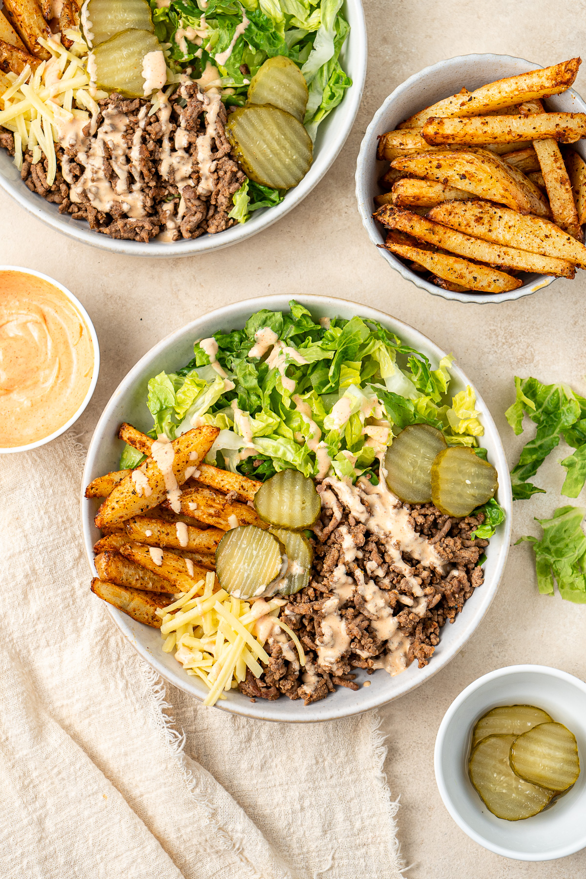 Overhead of a burger bowl with special sauce and pickles with potato chips.