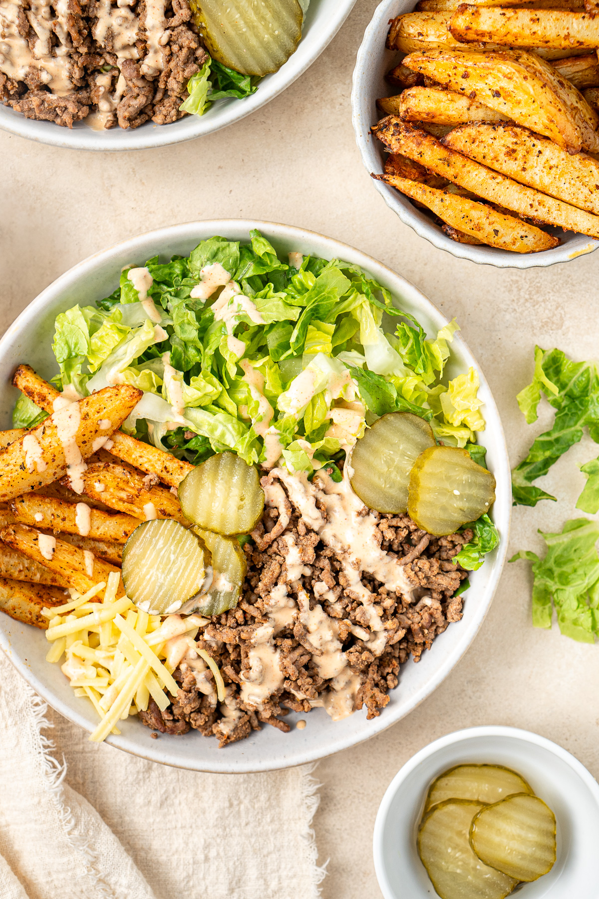 Close up of a burger bowl salad with special sauce and crispy potato fries.