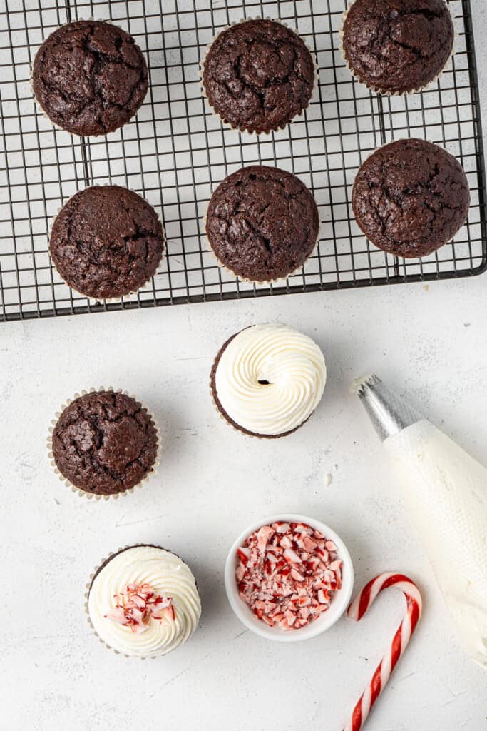 Piping frosting onto the chocolate cupcakes.