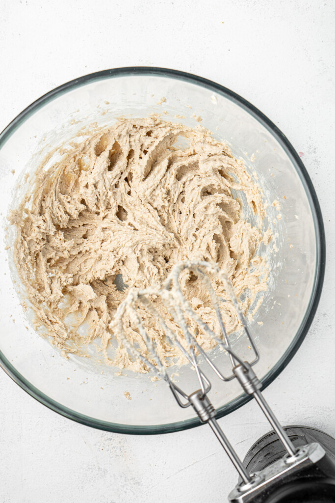 Beating together the dairy free butter and sugars in a glass bowl with an electric mixer.