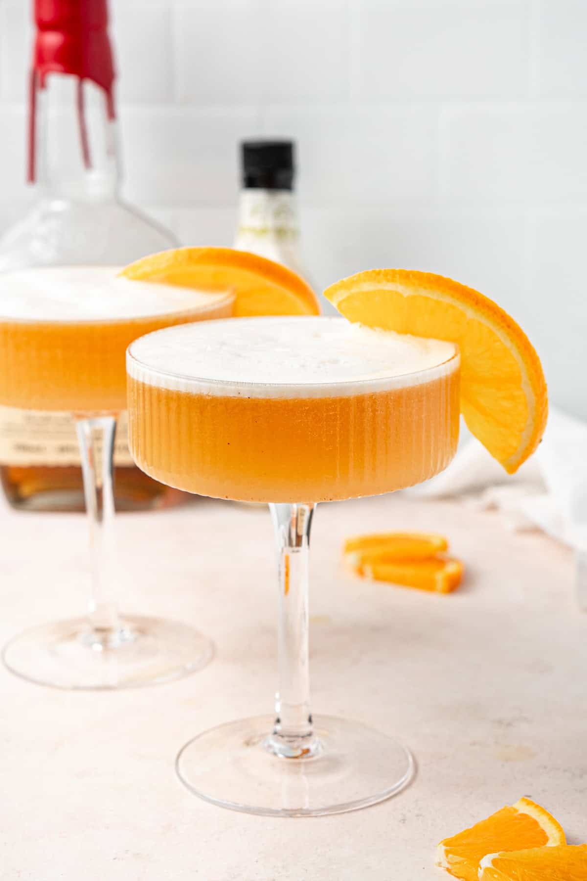 A gingerbread whiskey sour in a coup glass with a slice of orange.