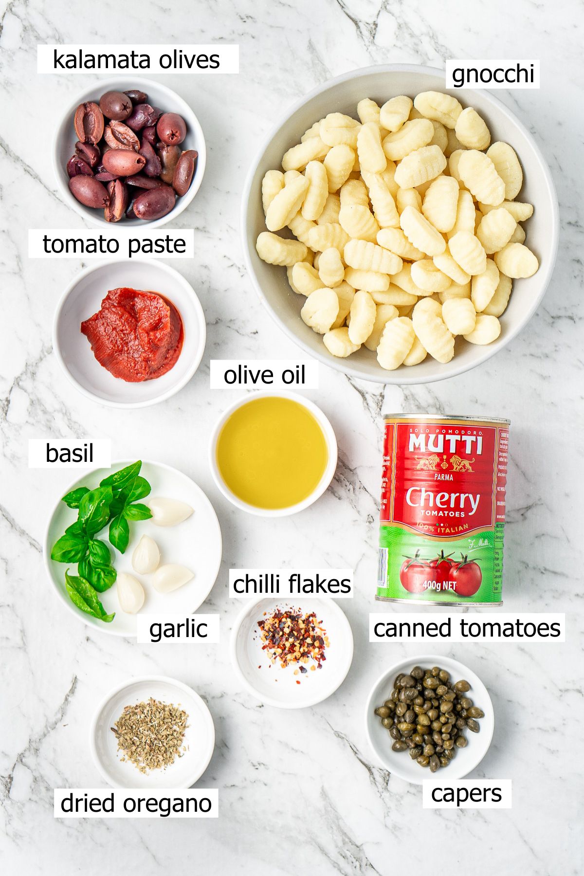 All ingredients needed to make gnocchi puttanesca laid out in bowls.