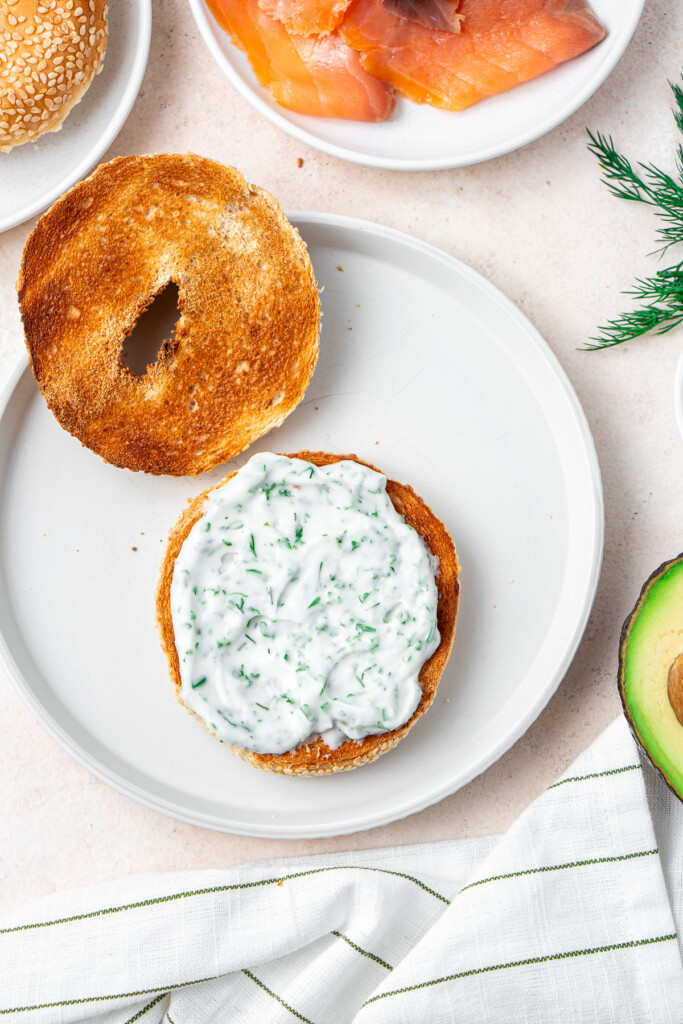 Adding the herb cream cheese to the bagel.