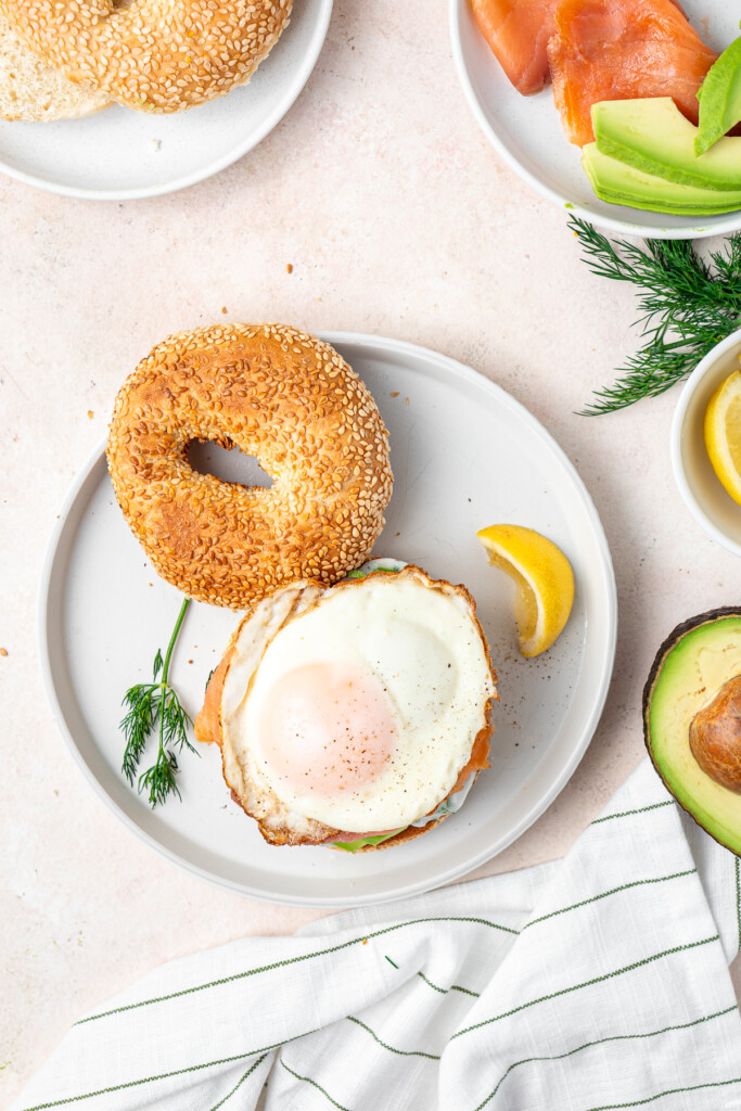 Topping the bagel with a fried egg.