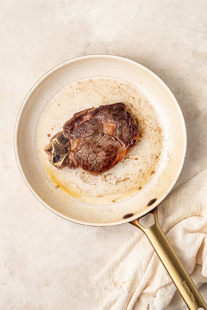 Cooked ribeye steak in a frying pan.