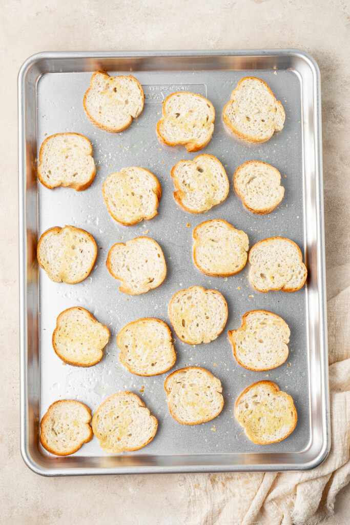 Toasted baguette slices on a baking tray.