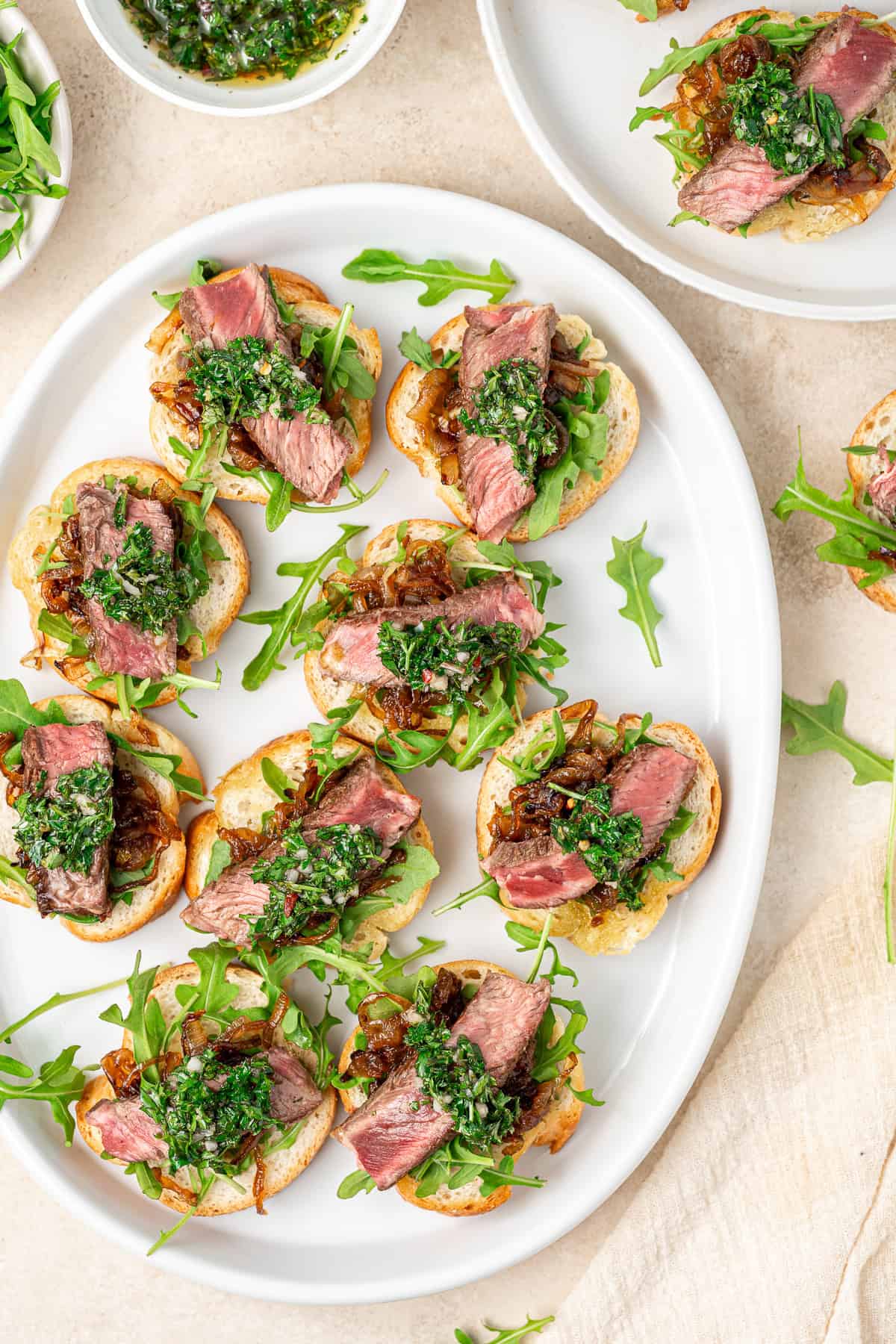 Steak crostini with chimichurri on a serving plate.