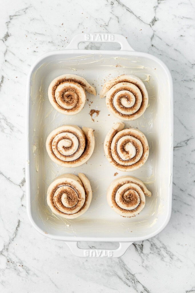 The cinnamon rolls in the baking dish ready for the second rise.