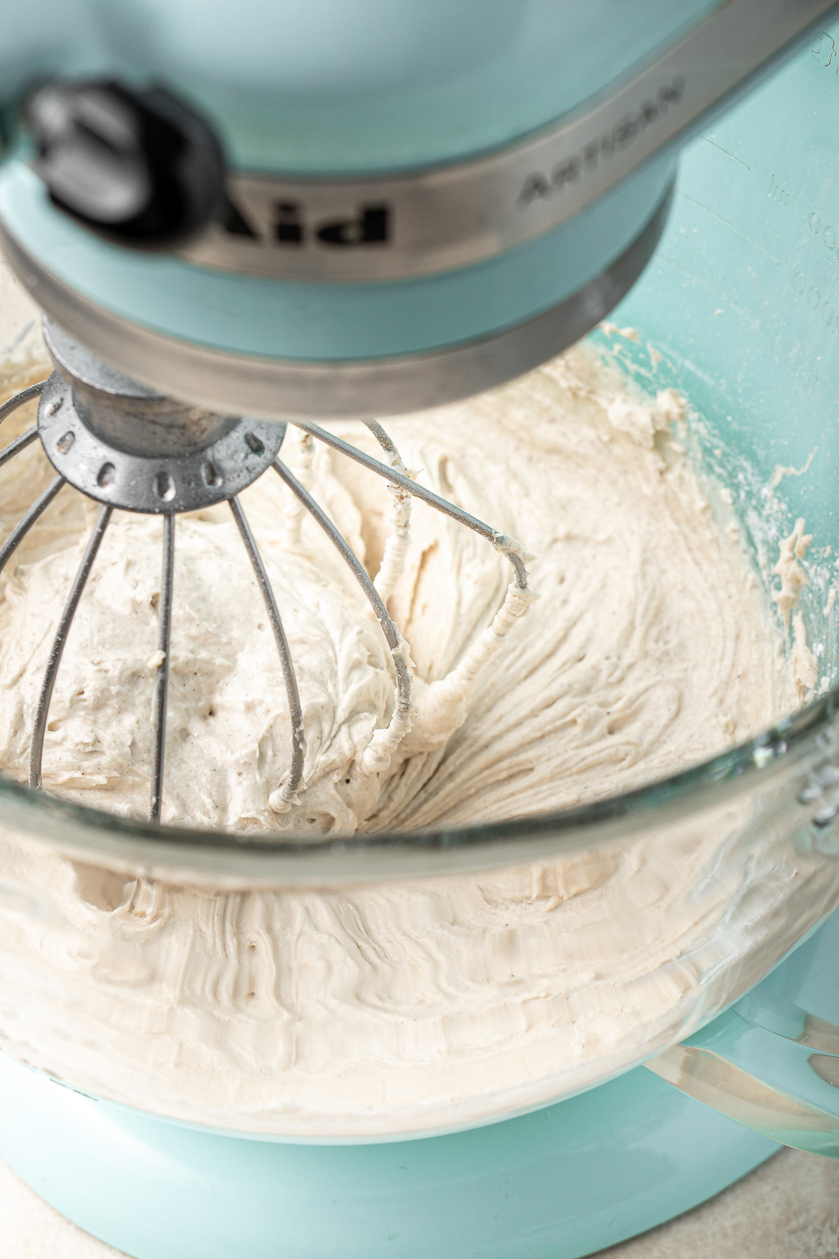 Beating together creamy buttercream frosting in a stand mixer.