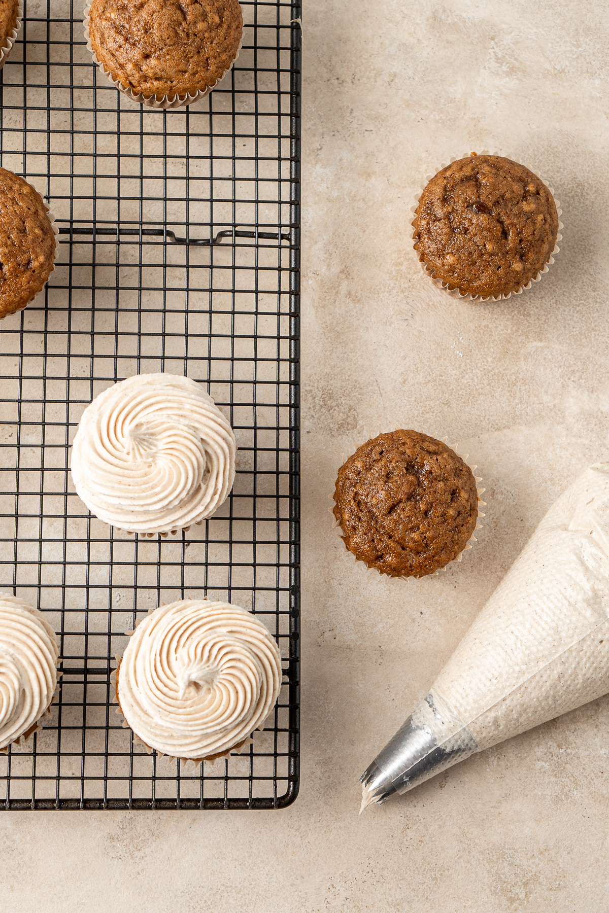 Piping vegan cinnamon buttercream onto gingerbread cupcakes.