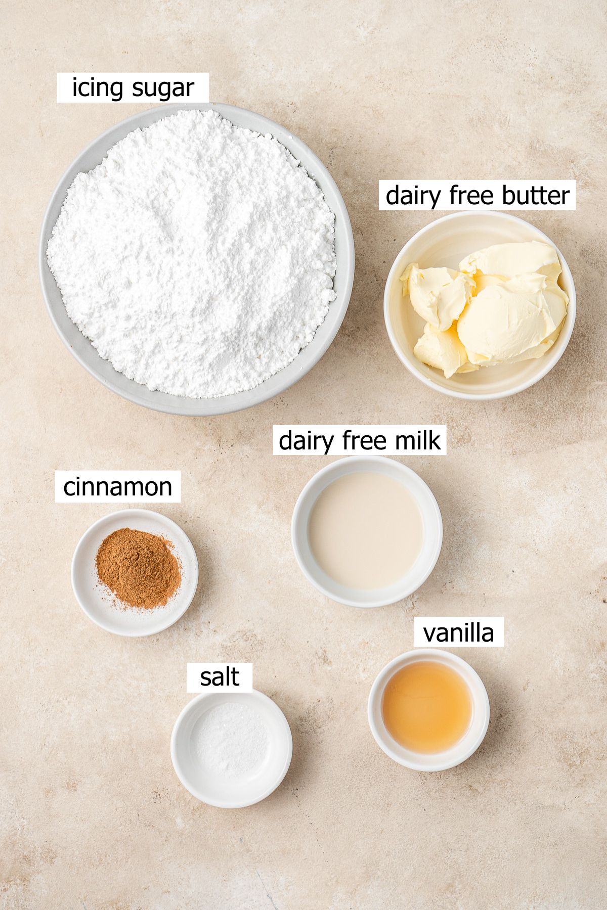 All ingredients needed to make cinnamon buttercream laid out in bowls.