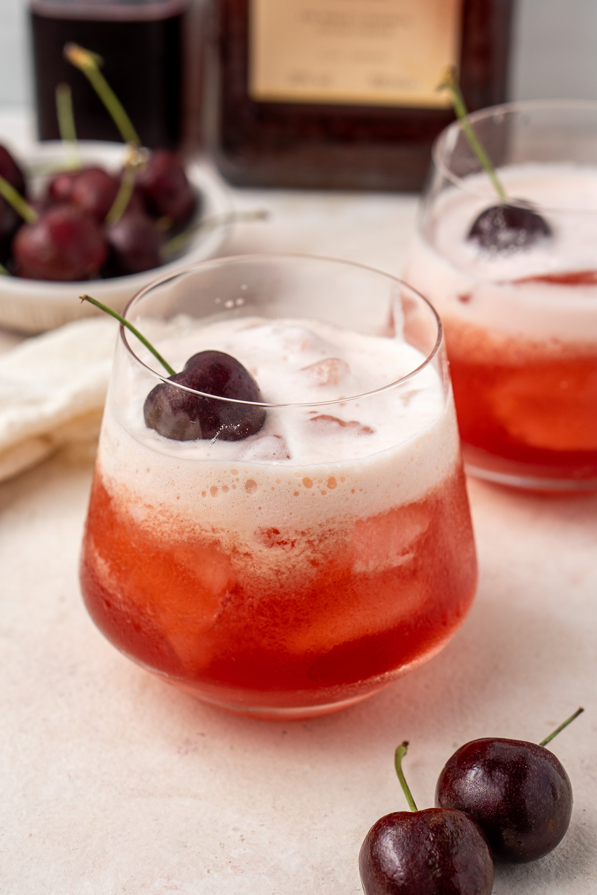 A close up of a glass of cherry amaretto sour.