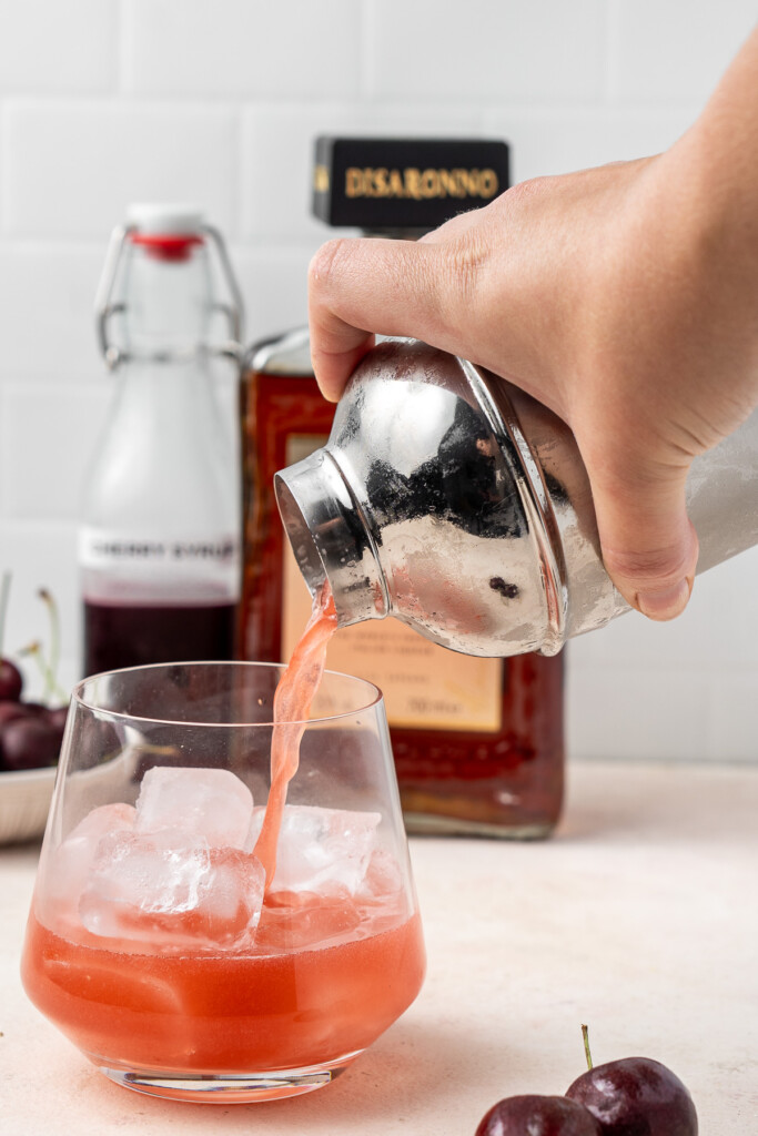 Pouring the cocktail into a glass filled with ice.