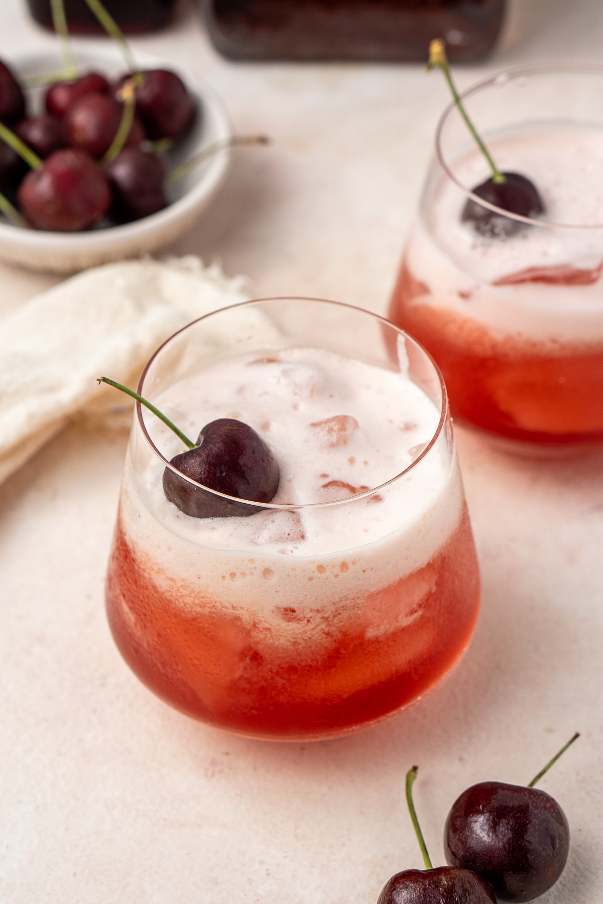 Cherry amaretto sour in a glass with a fresh cherry.