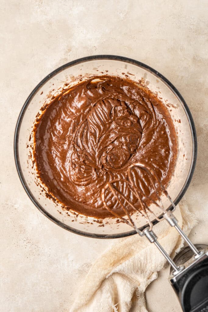 The cake batter in a glass bowl with electric mixer.