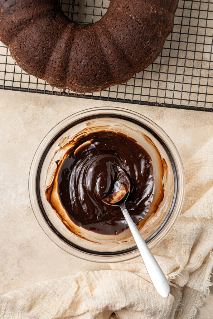 Mixing up the shiny chocolate ganache in a small bowl with a spoon.