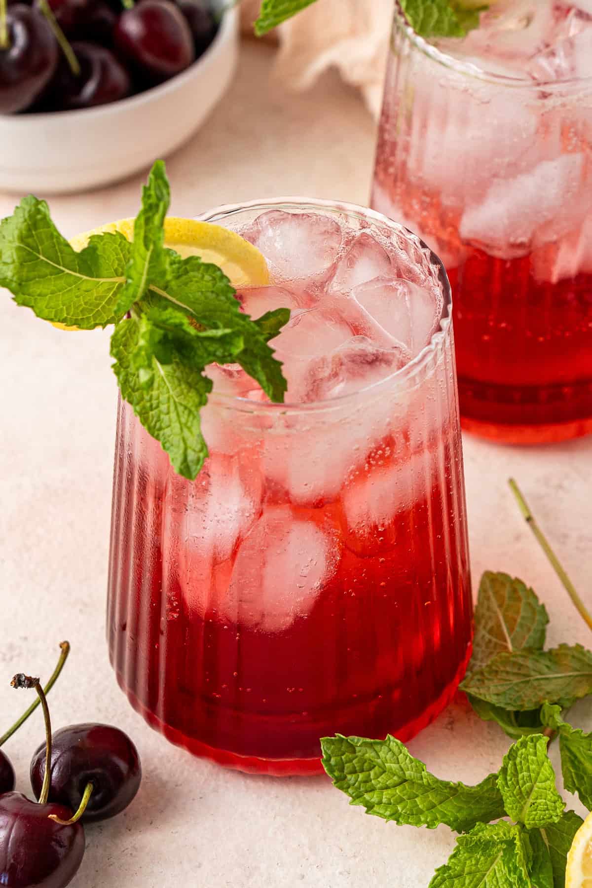 Close up of a cherry spritz with mint and a slice of lemon.