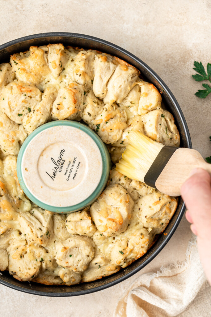 Brushing more garlic butter on top of the baked garlic bread.