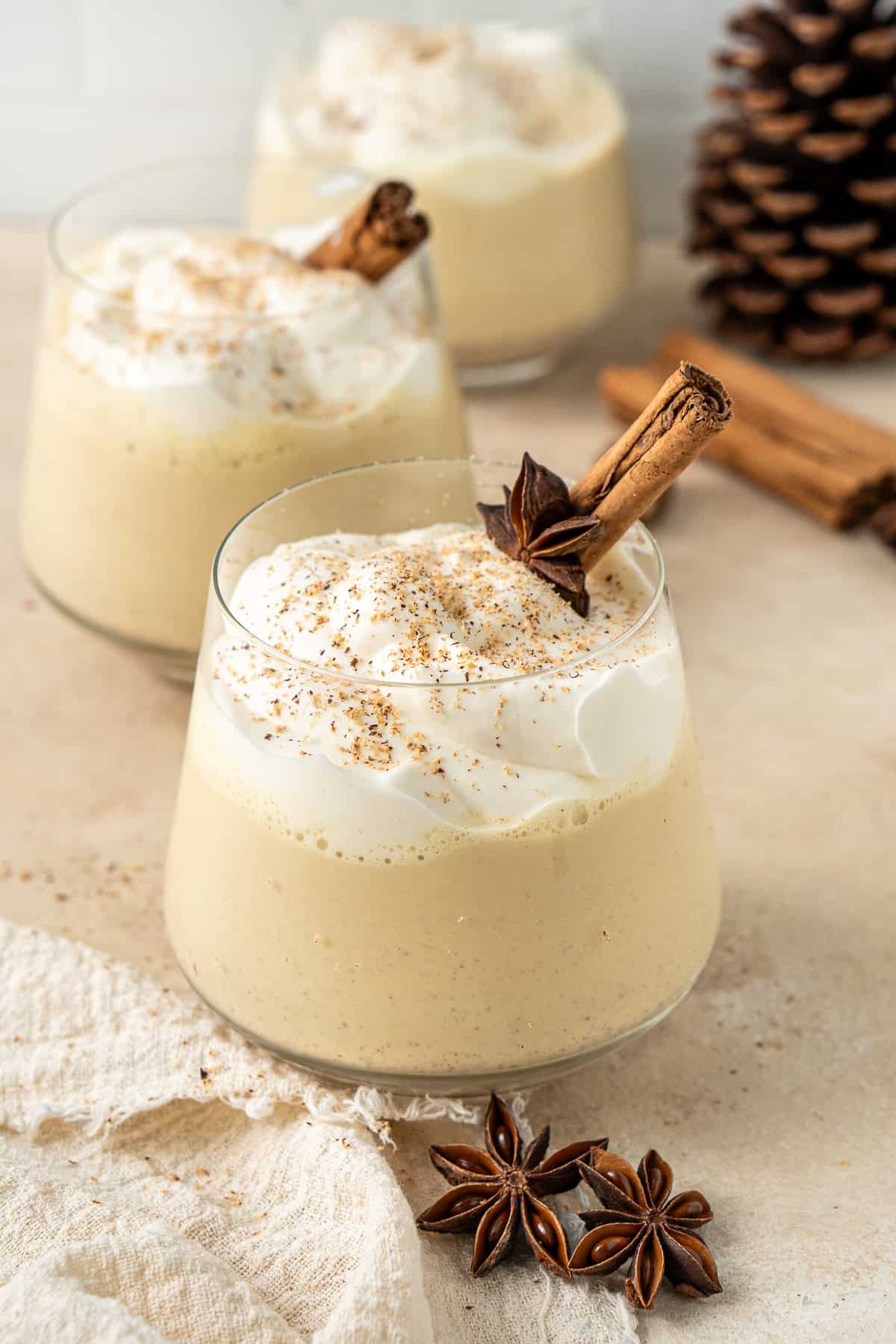 Vegan eggnog served in a glass with whipped cream and grated nutmeg.