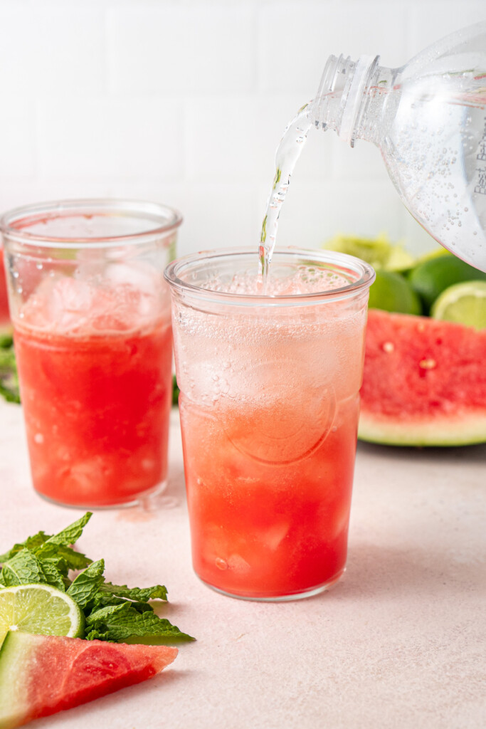 Adding soda water to the glass of watermelon juice with ice. 