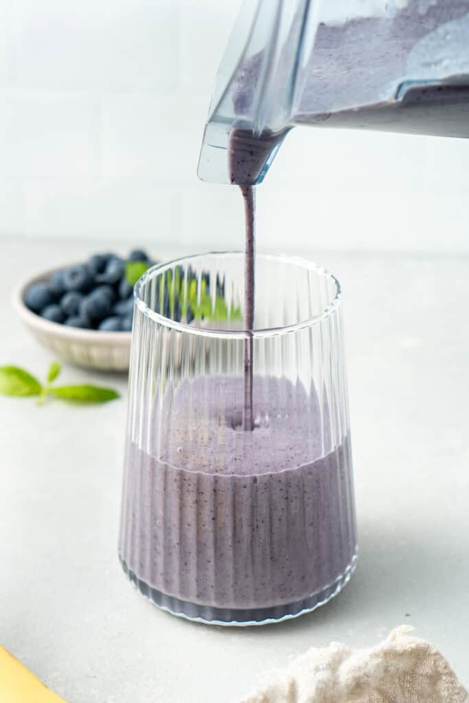 Pouring the smoothie from the blender jug into a glass.