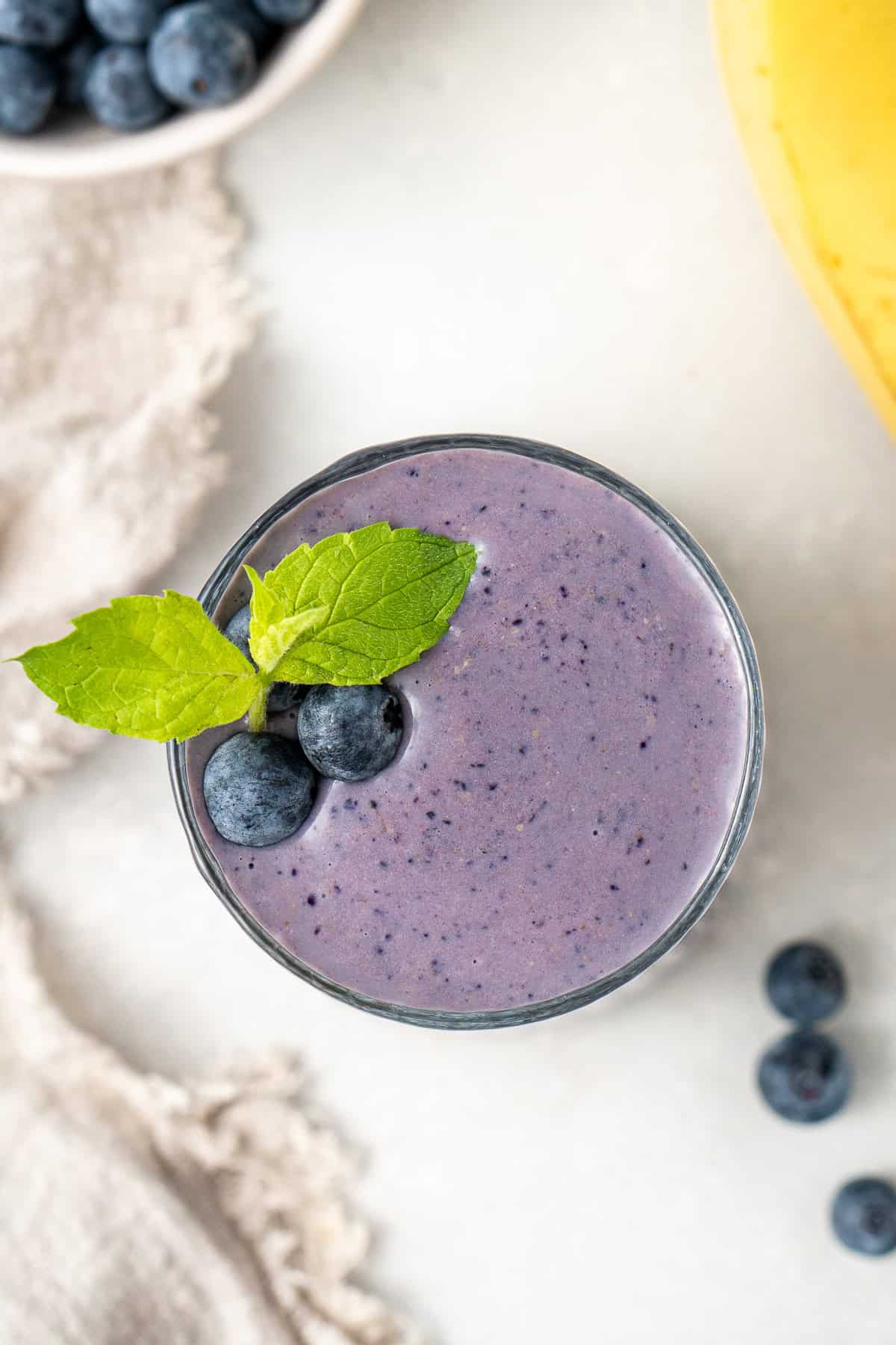 Overhead of the banana blueberry smoothie topped with fresh blueberries and a bit of mint.