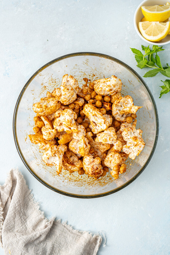 The chickpeas and cauliflower in a mixing bowl with the spices.