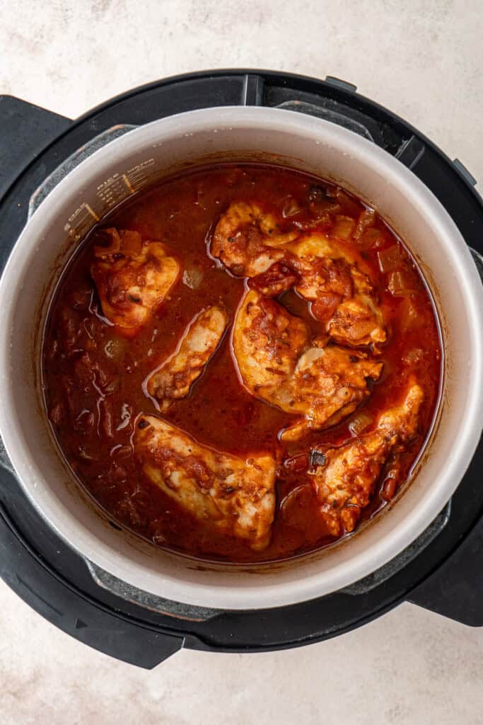 The cooked chicken and sauce in the bowl of the slow cooker.