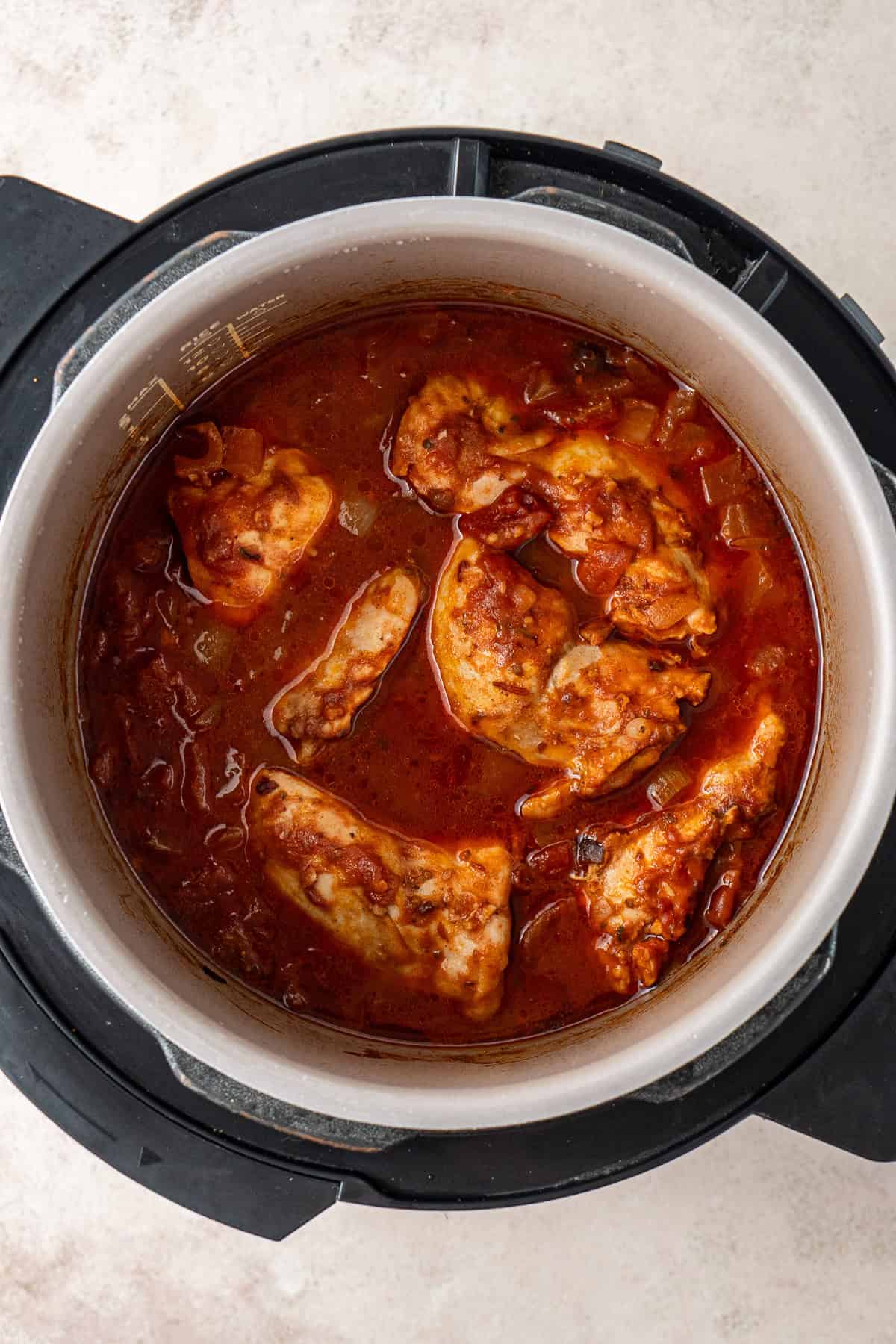 The cooked chicken and sauce in a slow cooker.