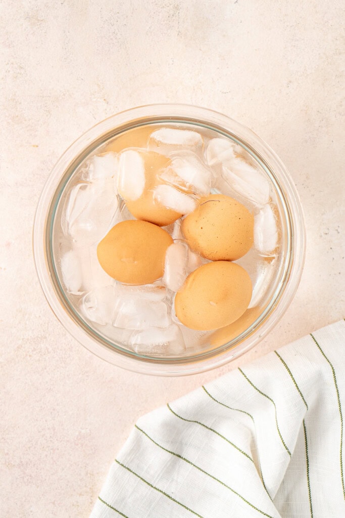 Adding the eggs to a bowl of ice water.