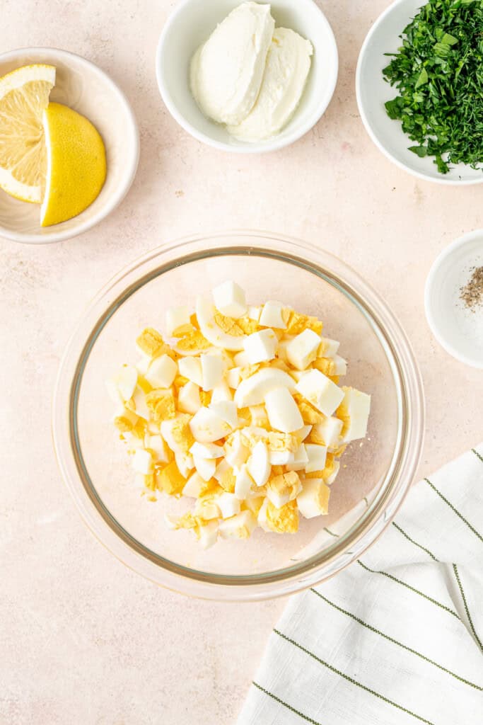 Adding the chopped hardboiled eggs to a bowl.