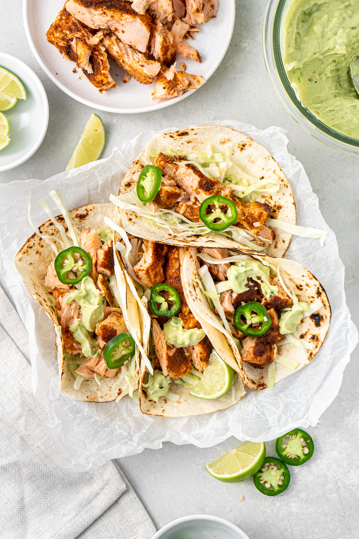 Grilled salmon tacos on a plate with fresh jalapeños as garnish.