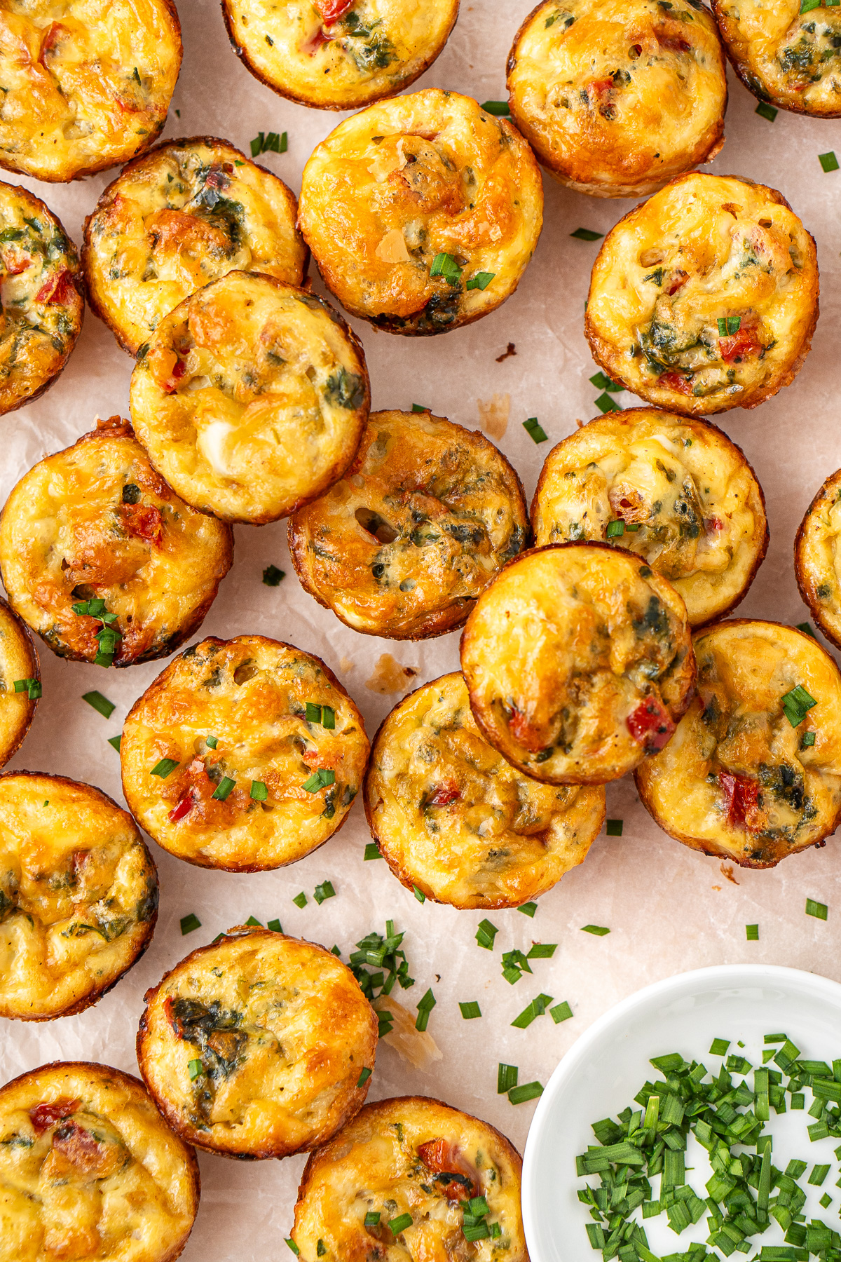 Lots of mini vegetarian quiches with chopped chives.