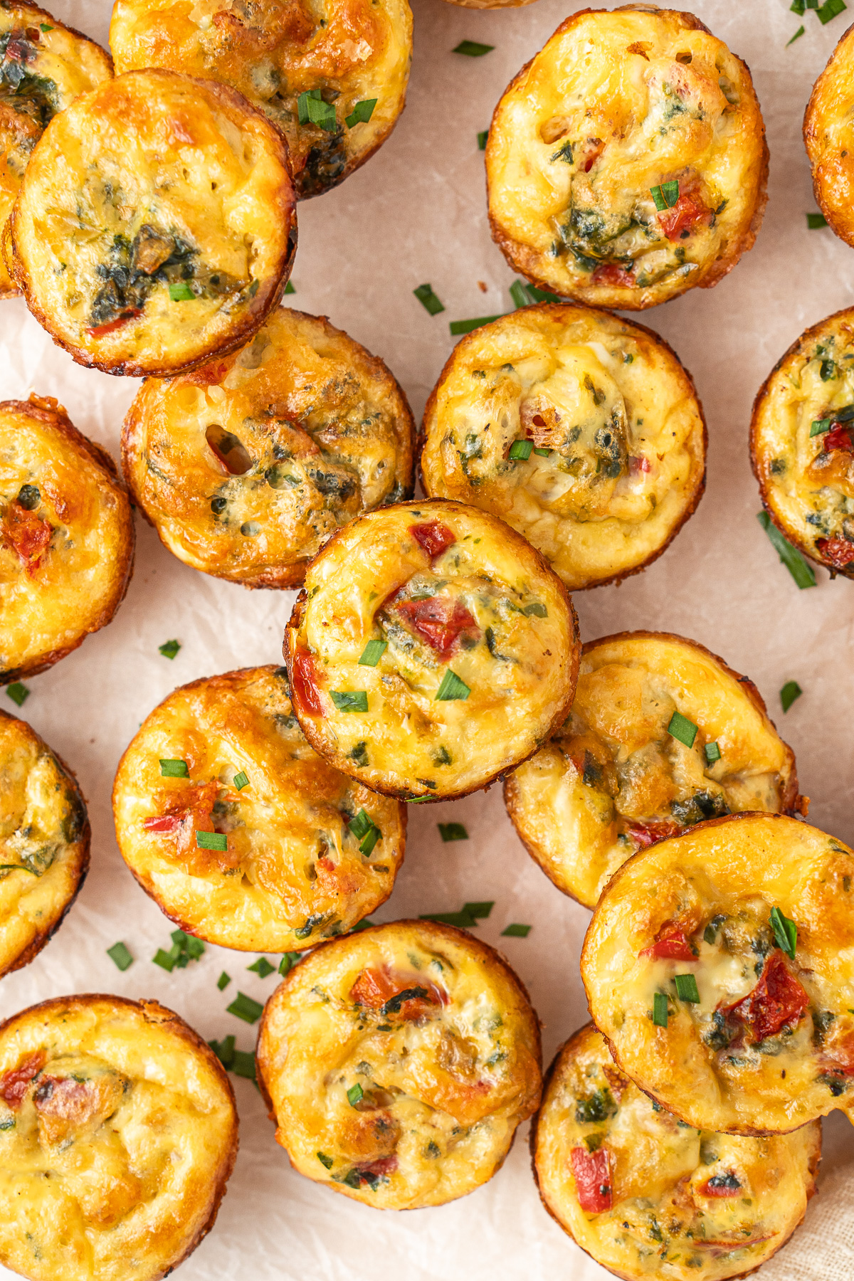 Mini vegetarian quiches laid out and garnished with chopped chives.