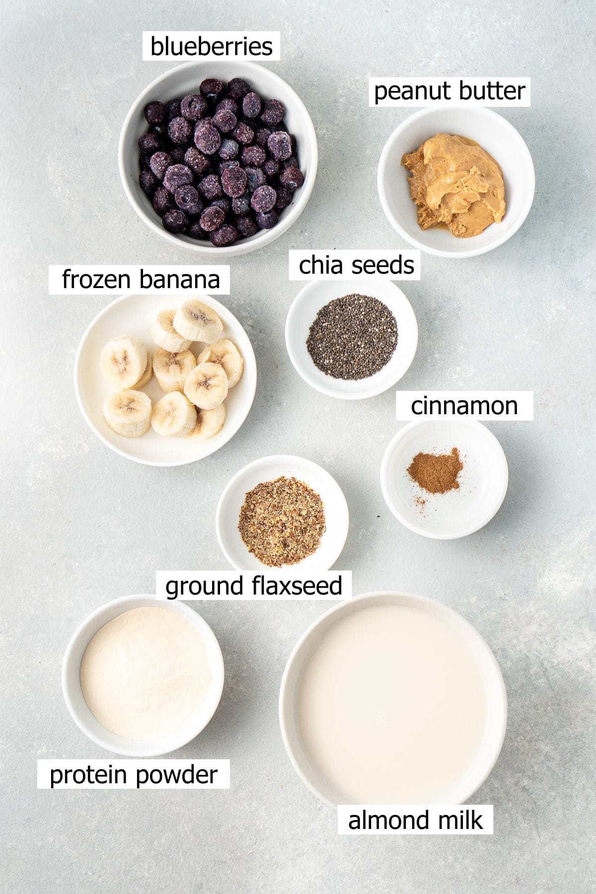 All ingredients needed to make a dairy free blueberry banana smoothie laid out in small bowls.