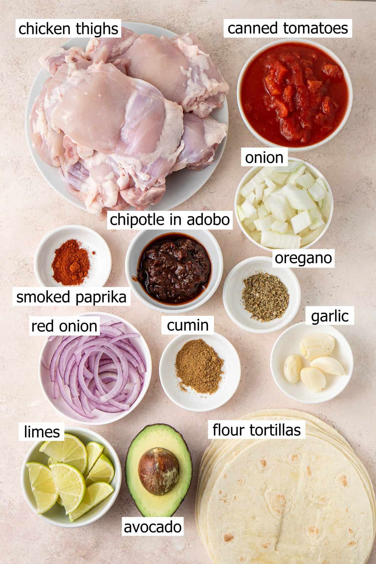 All ingredients needed to make chicken tinga tacos laid out in bowls.