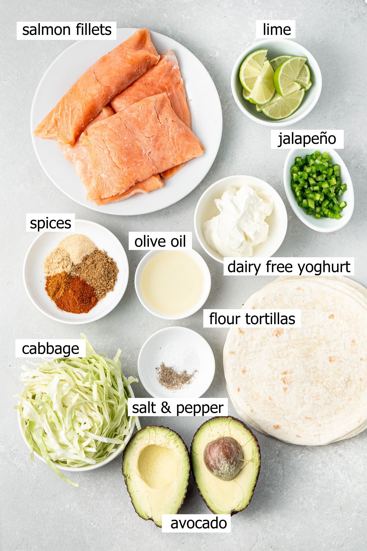 All ingredients needed to make grilled salmon tacos with avocado crema laid out in small bowls.