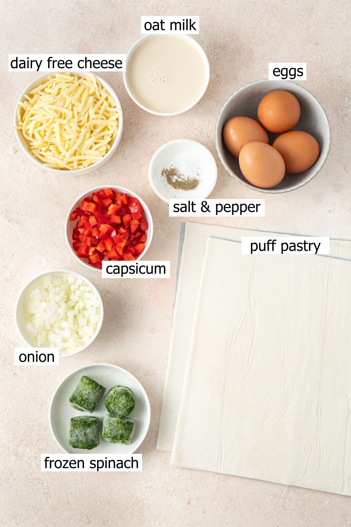 All ingredients needed to make mini quiches laid out in small bowls.