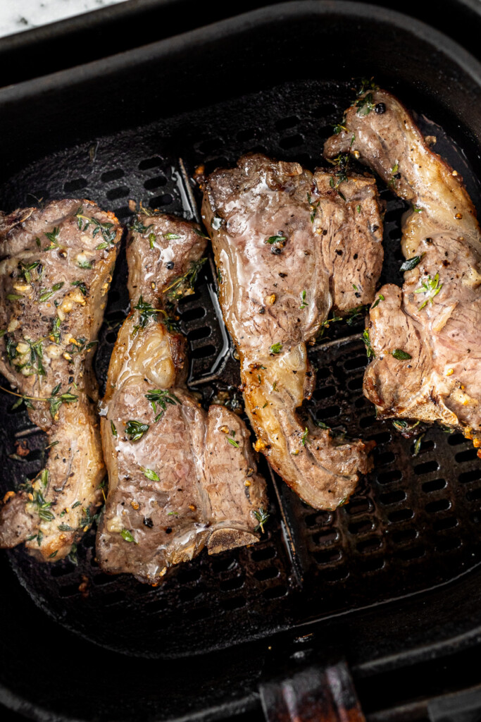 Cooked lam chops in the basket of the air fryer.