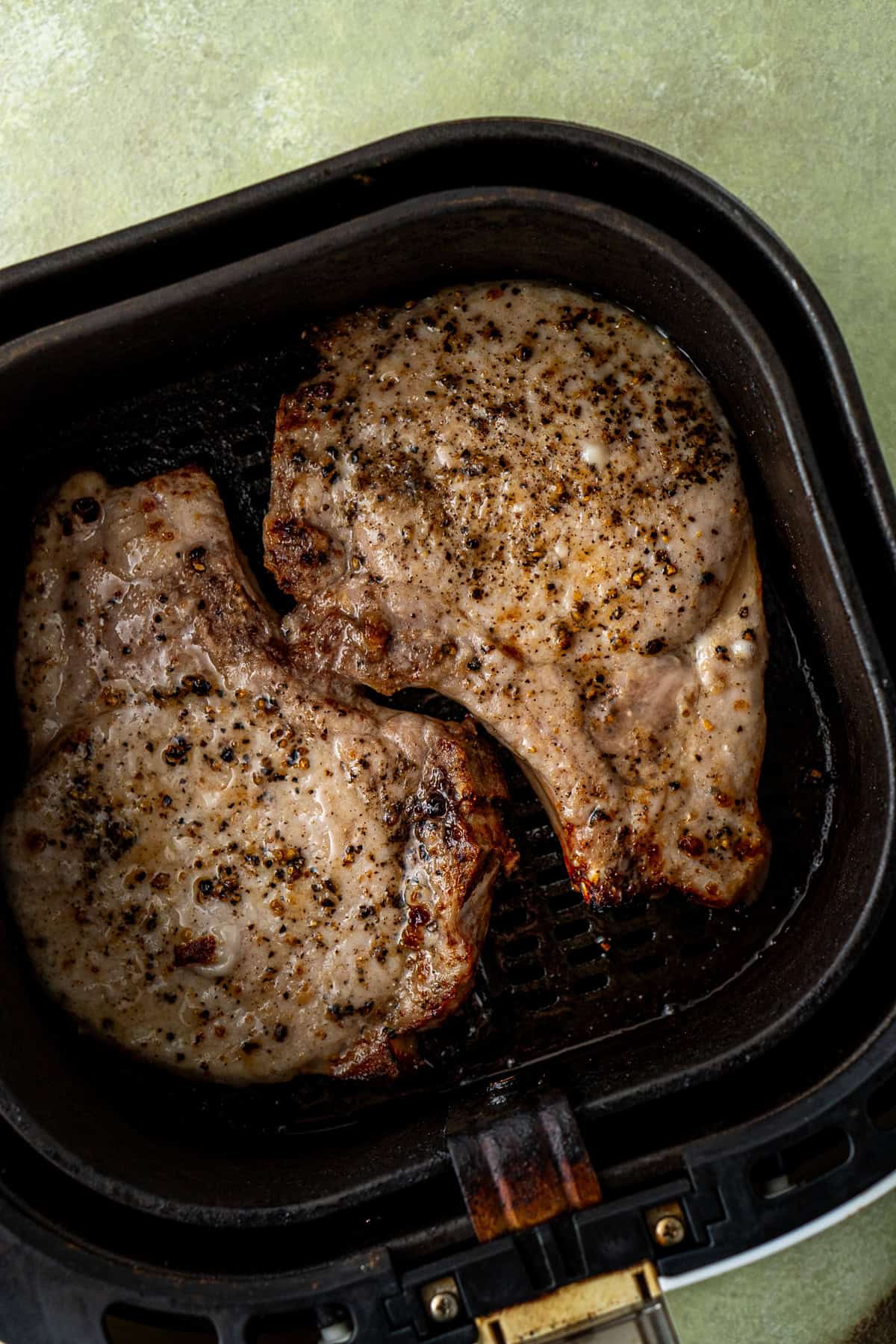 Close up of the cooked pork chops in the basket of the air fryer.