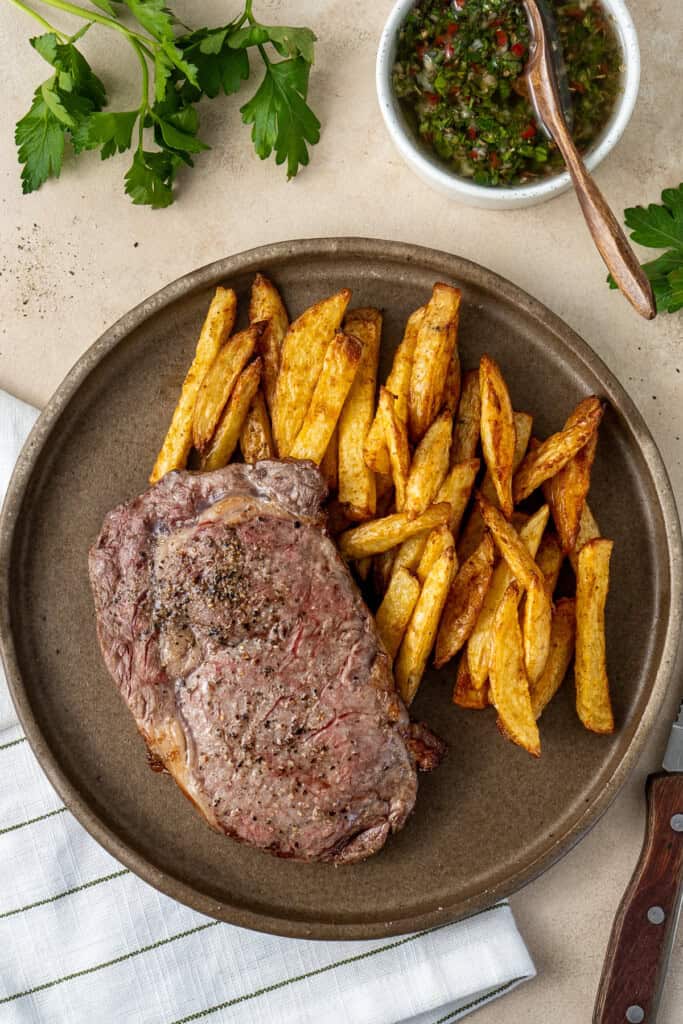 Serving a steak on a plate with oven baked chips.