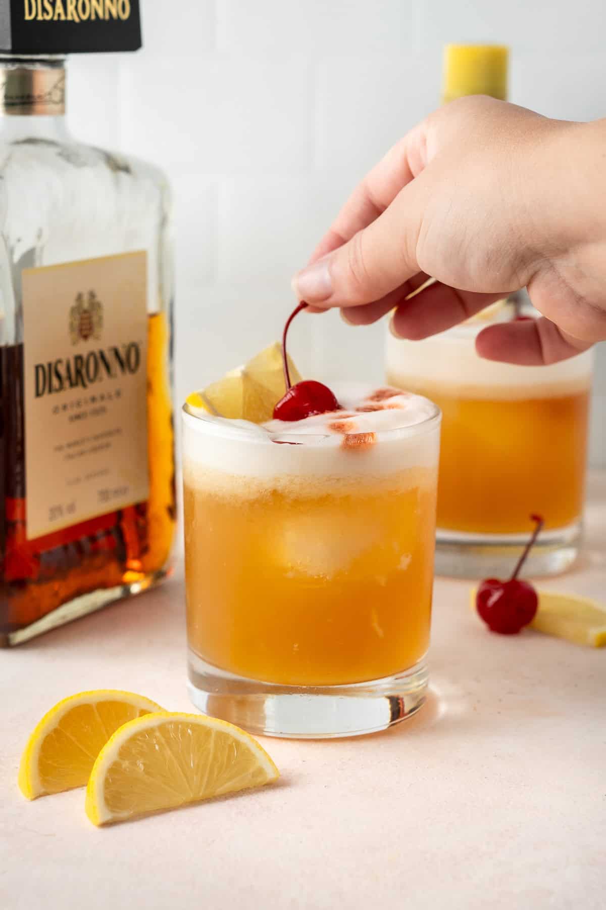 Adding a cherry garnish to an amaretto sour.