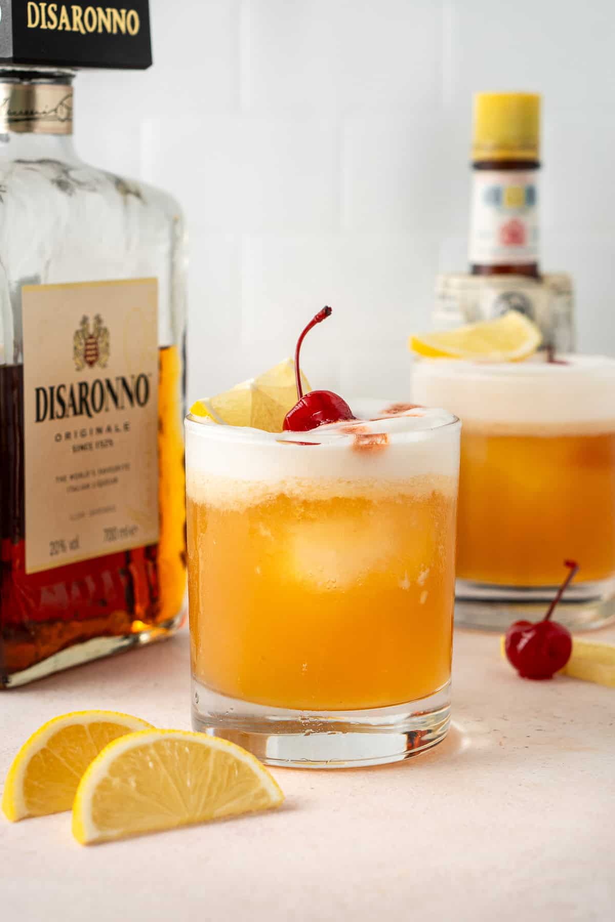 Two classic amaretto sour cocktails with garnish.