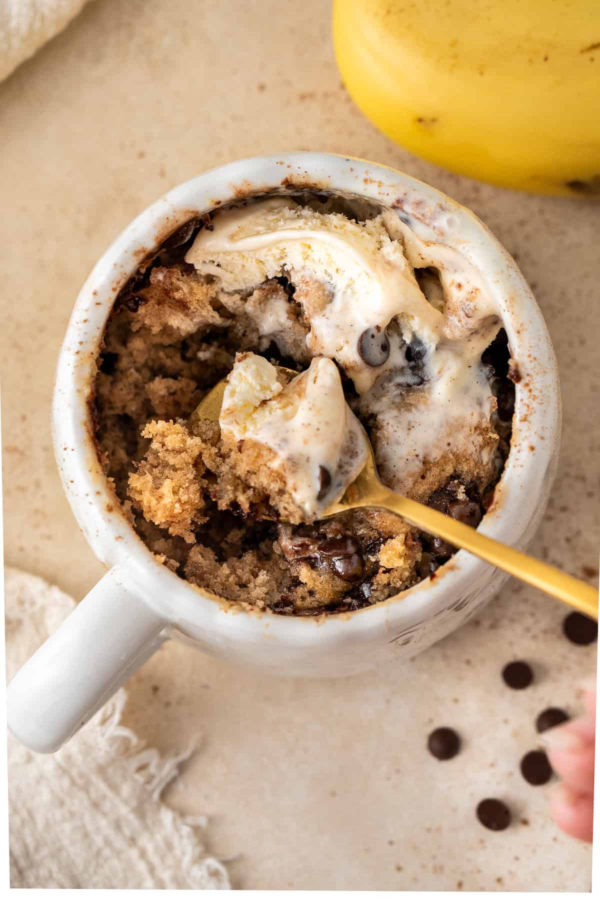 A spoon taking a bite of the banana bread mug cake with cinnamon.