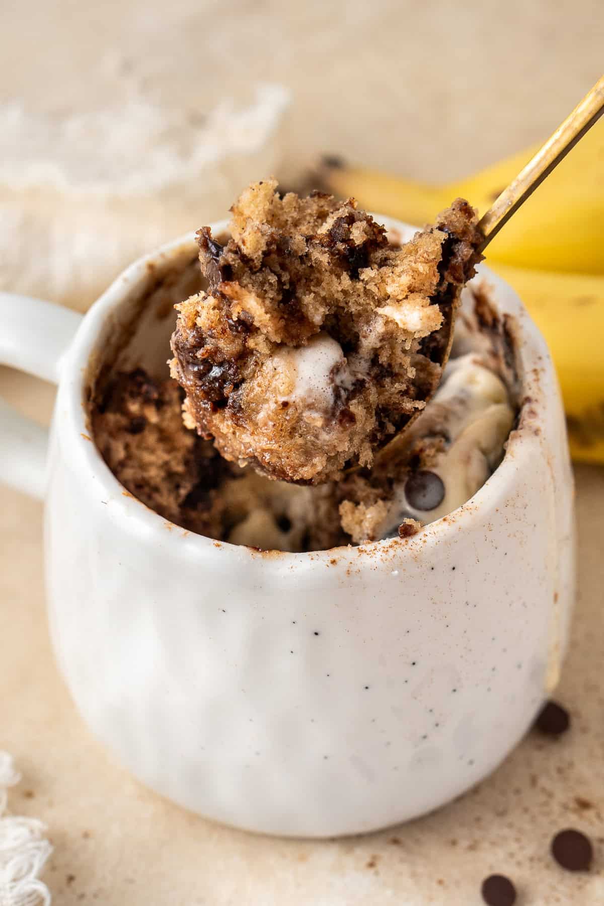 A spoon full of banana bread mug cake with chocolate chips.