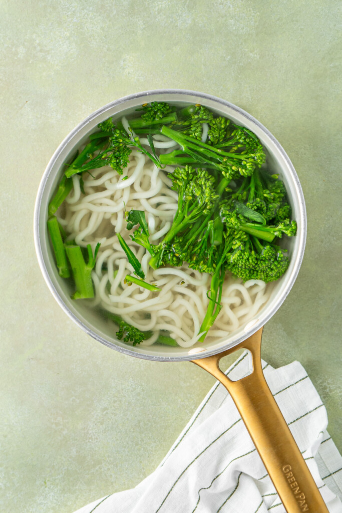 Cooking the broccolini and udon noodles in a pot of water.