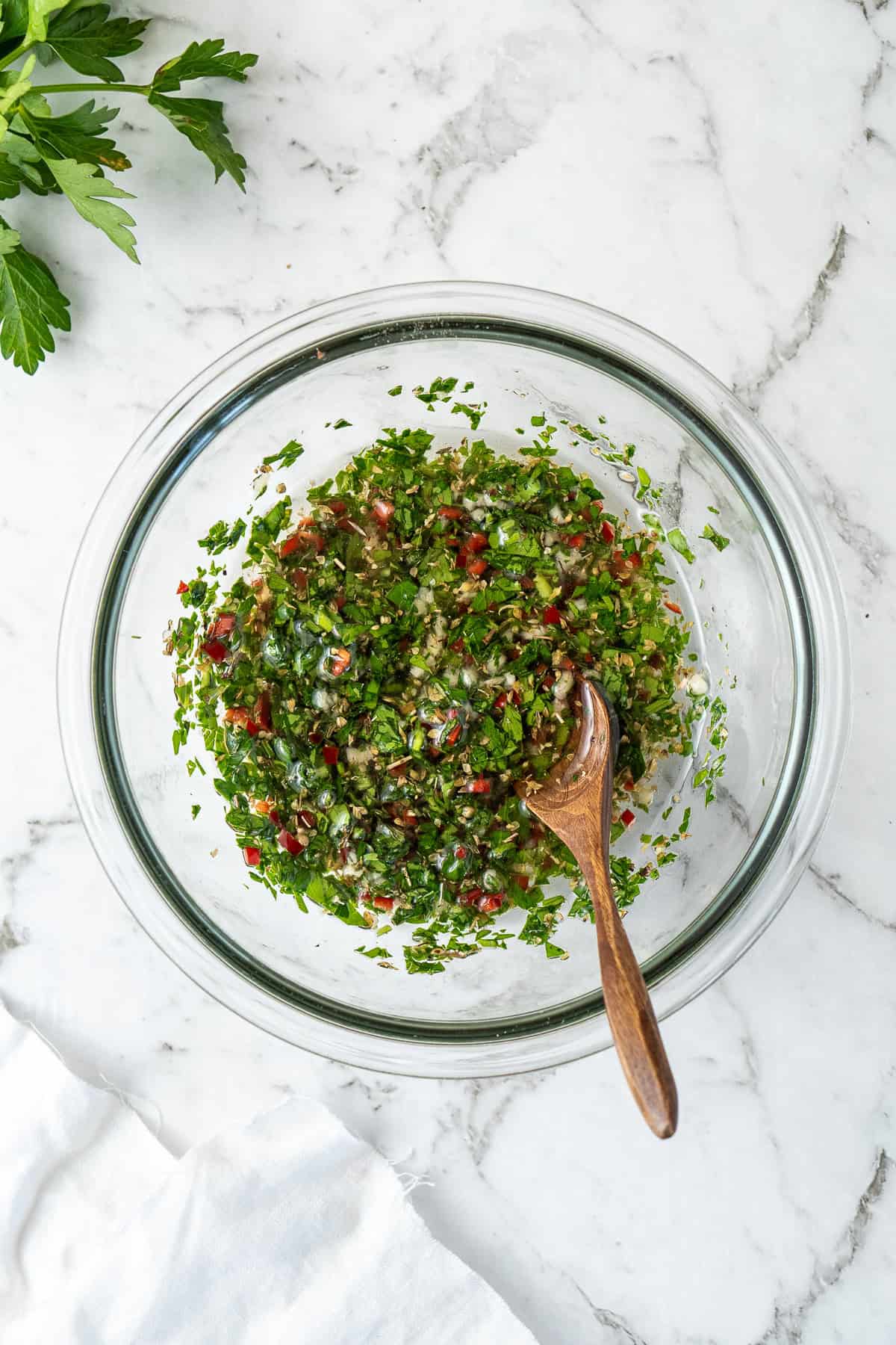 Mixing the chimichurri in a glass bowl.