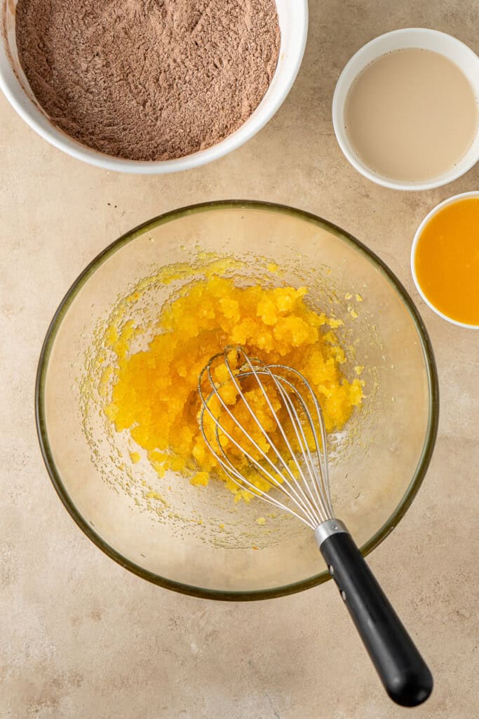 Whisking together the orange zest, canola oil and white sugar.