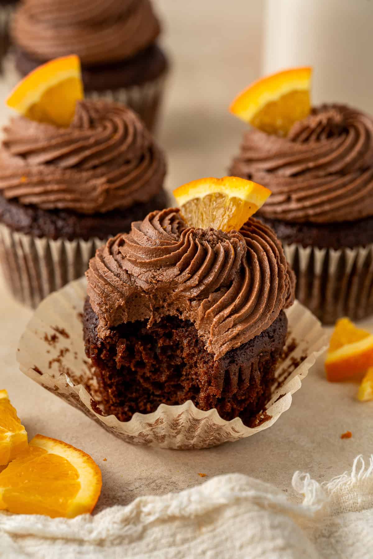 A chocolate orange cupcake with a bite taken.