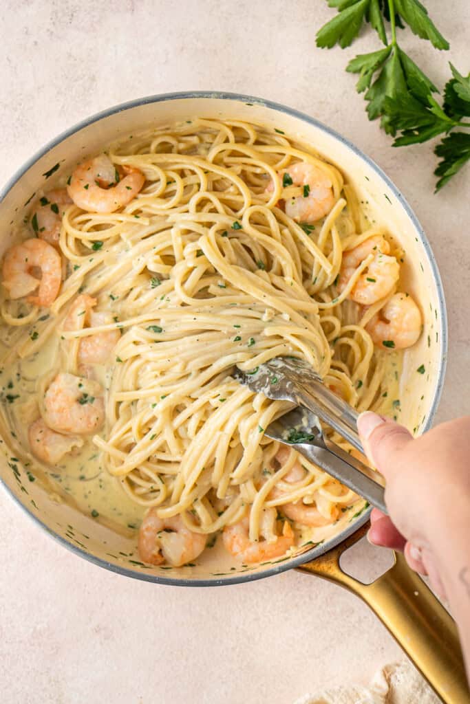 Mixing through the cooked pasta in the creamy sauce.